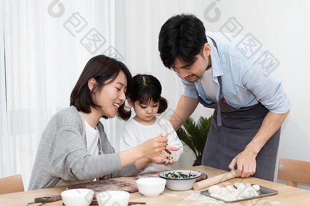 年轻的亚洲妈妈爸爸使饺子女儿