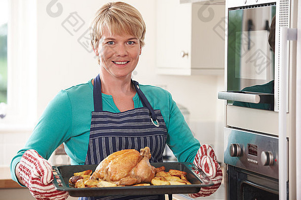 女人厨房持有托盘烤鸡
