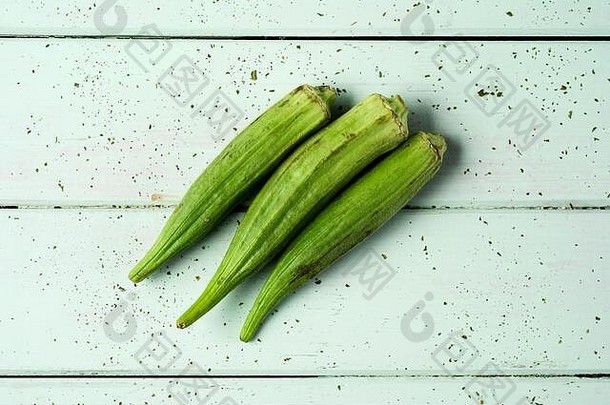 高角视图生秋葵豆荚苍白的绿色木表格工作台面