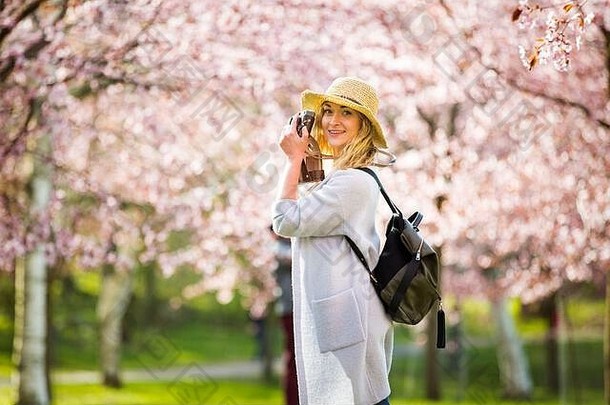 肖像美丽的女人稻草他旅行美丽的公园樱桃树布鲁姆采取照片复古的相机旅游背包