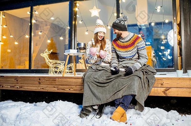 年轻的夫妇气候变暖格子棉花糖坐着阳台现代房子山杜尔尼格冬天假期