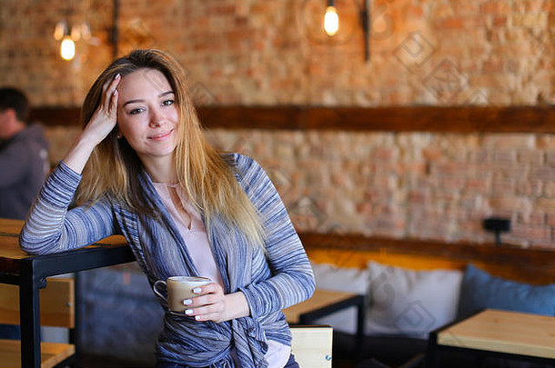满意女孩坐着表格杯卡布奇诺咖啡舒适的咖啡馆不寻常的室内
