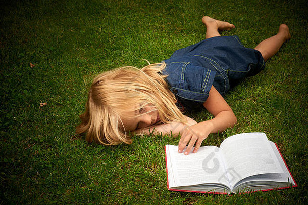 可爱的金发碧眼的女孩阅读书草