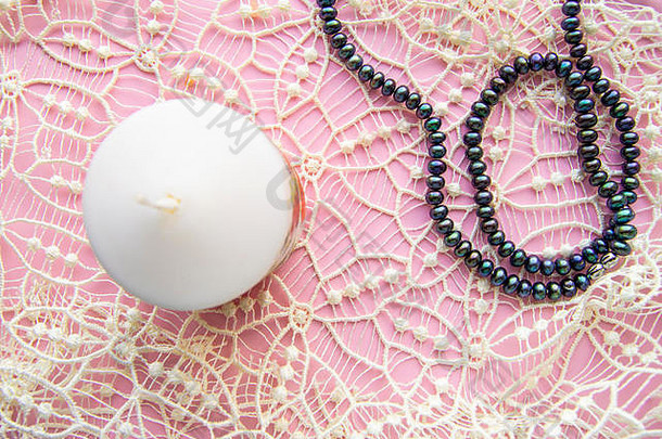 平铺粉红色的背景优雅的白色昂贵的花边优雅的黑色的珍珠蜡烛浪漫的风格