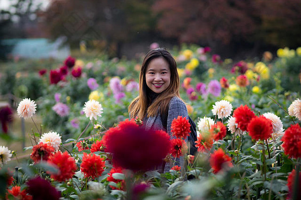 美丽的女人摆姿势红色的花日本花园