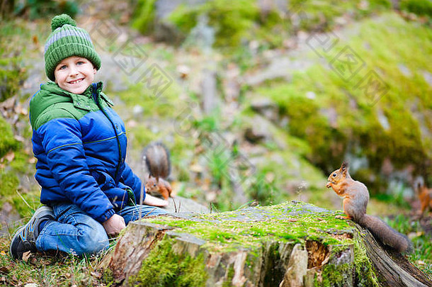 可爱的男孩喂养松鼠秋天公园