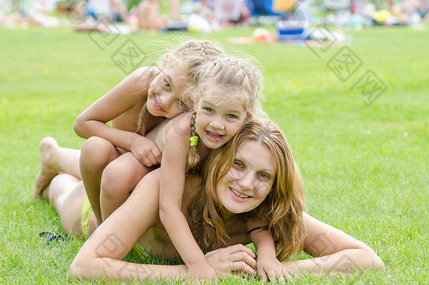 女儿幸福的坐妈妈回来热夏天一天放松绿色草坪上