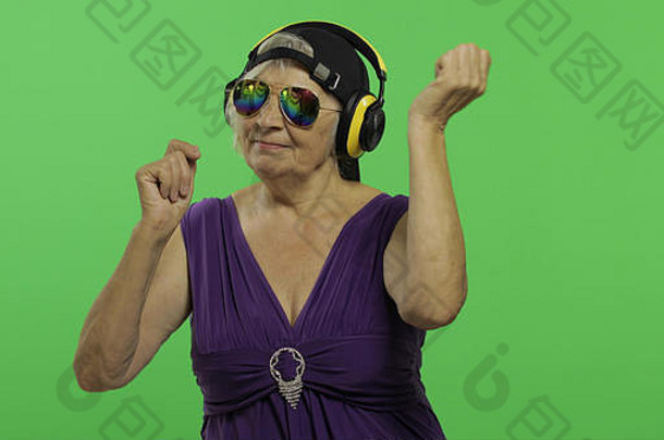 上了年纪的女人听音乐耳机舞蹈漂亮的快乐祖母太阳镜帽的地方标志文本浓度关键绿色屏幕背景