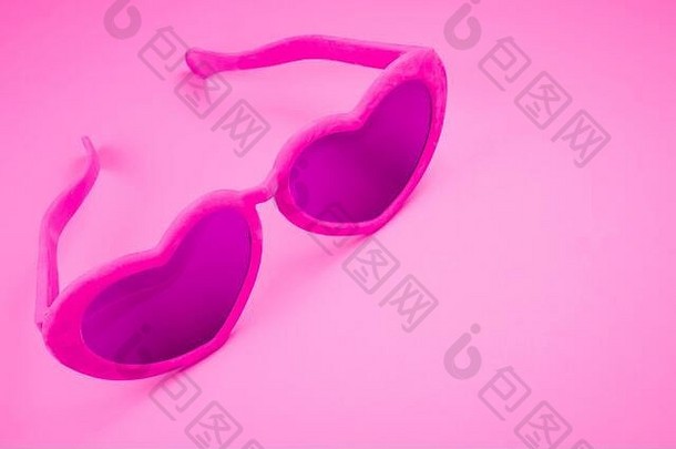 引人注目的一对心形的眼镜坐着明亮的粉红色的背景