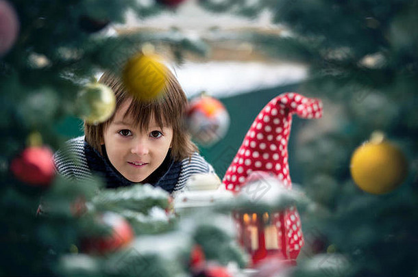 <strong>可爱</strong>的孩子男孩站圣诞节树快乐脸软美丽的雪下雪冬季