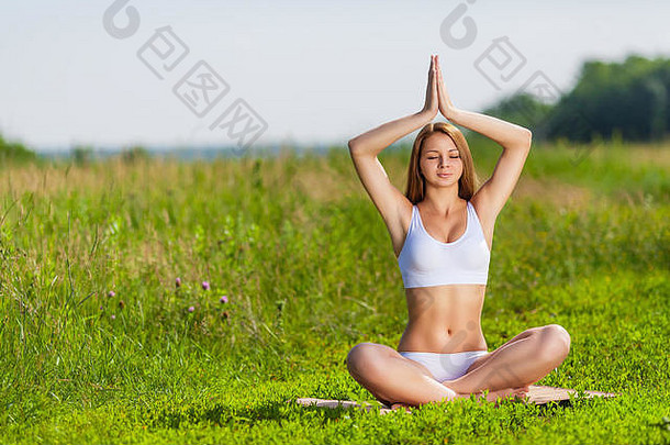 年轻的女人练习瑜伽冥想在户外自然