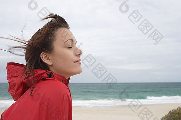 年轻的女人穿红色的雨衣海滩