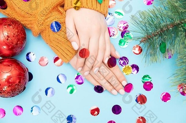 女美丽的手修指甲指甲温暖的毛衣红色的圣诞节球一年蓝色的背景前视图