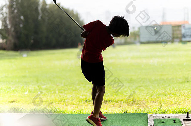 年轻的亚洲男孩练习高尔夫球摇摆不定的高尔夫球开车范围