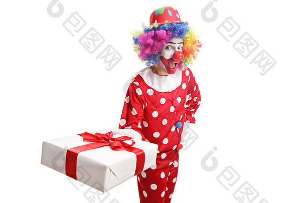 有趣的小丑持有礼物盒子使鬼脸孤立的白色背景