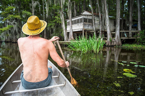 男人。他坐着前面独木舟划黑暗沼泽场景喀多人湖德州