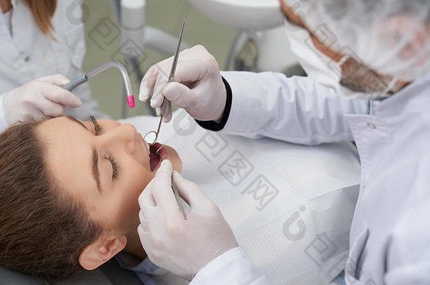 女人打开口说谎牙医椅子opn口专业医生持有恢复仪器治疗牙齿口腔健康护理
