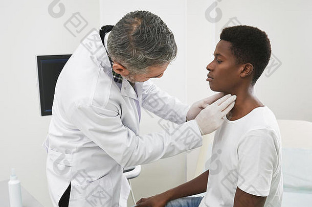 治疗师检查脖子非洲病人医疗内阁医生触诊淋巴节点手指医生穿白色医疗礼服手套男人。穿白色衬衫