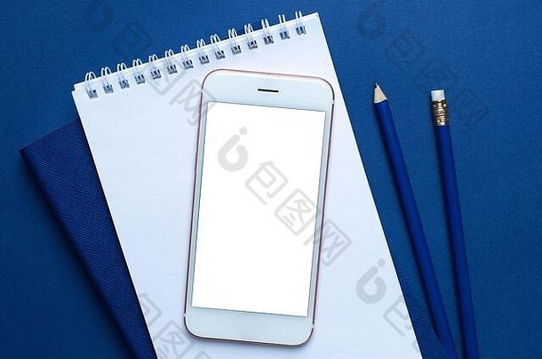 移动电话白色蓝色的办公室笔记本铅笔经典蓝色的背景前视图时尚的颜色