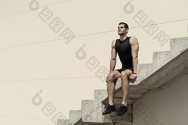 运动男人。适合强大的身体思考未来成功坐着混凝土楼梯高墙复制空间文本设计