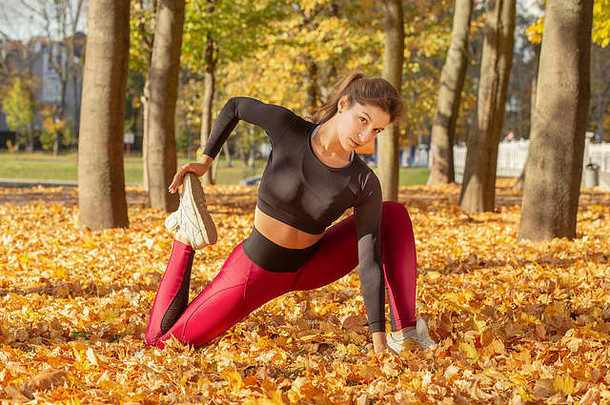 苗条的运动女人伸展运动秋天城市公园