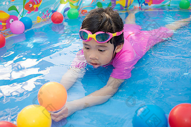 婴儿女孩粉红色的西装玩水球蓝色的小孩池