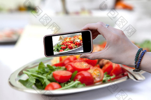 女人持有电话拍摄沙拉红色的番茄