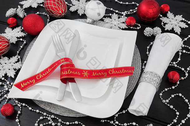 圣诞节晚餐表格设置白色瓷盘子丝带冬青银红色的小玩意装饰餐具餐巾