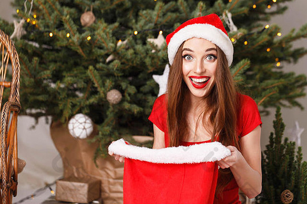 惊讶圣诞节女人穿圣诞老人他红色的衣服坐着地板上一年云杉袋震惊了礼物一年圣诞节假期记忆礼物购物折扣商店雪少女圣诞老人老人化妆发型狂欢节