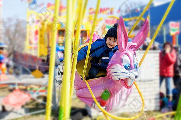 可爱的男孩摆动粉红色的兔子娱乐公园
