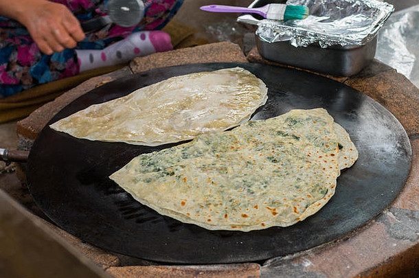 土耳其女人准备Gozleme传统的菜形式面包塞绿色奶酪包装内部烤锅被称为萨吉