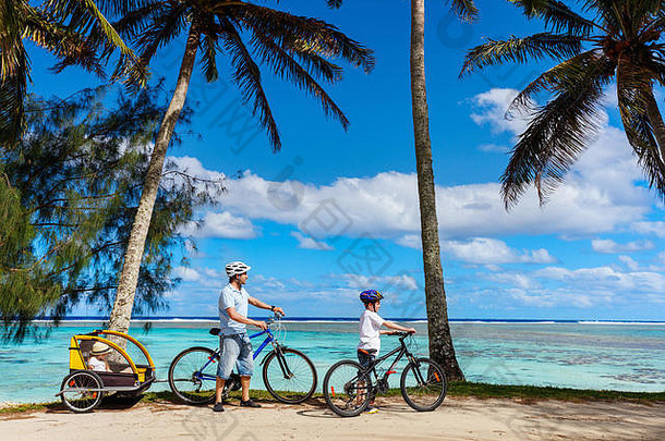 家庭父亲孩子们骑自行车热带海滩