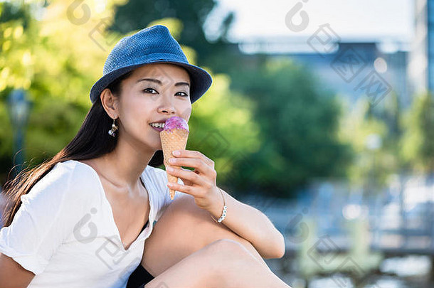 年轻的日本女人吃冰奶油在户外