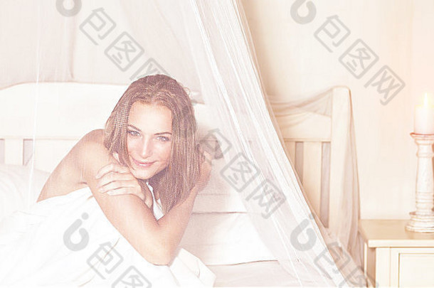 肖像温柔的浪漫的女人坐着床上温柔的透明的帷幔支出周末奢侈品水疗中心酒店