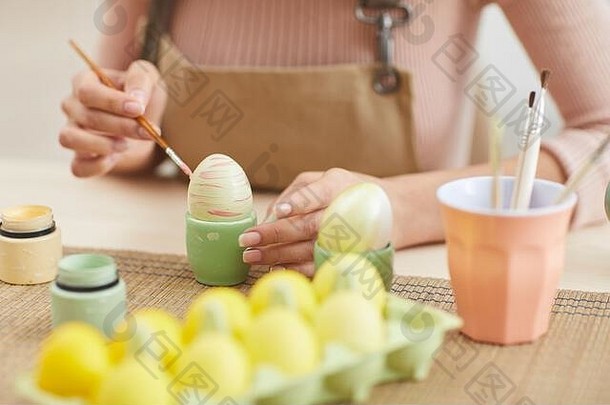 关闭年轻的女人绘画鸡蛋柔和的颜色复活节坐着表格厨房艺术工作室复制空间