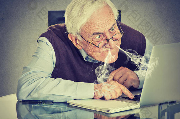强调上了年纪的男人。电脑吹蒸汽鼻子沮丧坐着表格孤立的灰色的墙背景高级人技术