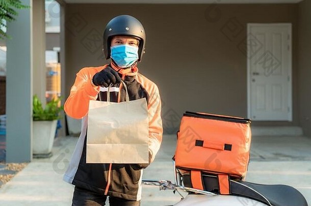 交付亚洲男人。穿保护面具橙色统一的准备好了发送交付食物袋前面客户锄头情况下盒子踏板车