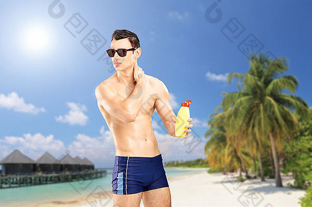 英俊的的家伙把太阳奶油桑迪海滩棕榈树水别墅别墅