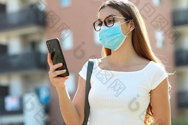 美丽的年轻的女人医疗面具消息传递聪明的电话城市街漂亮的女孩聪明的电话谈话户外
