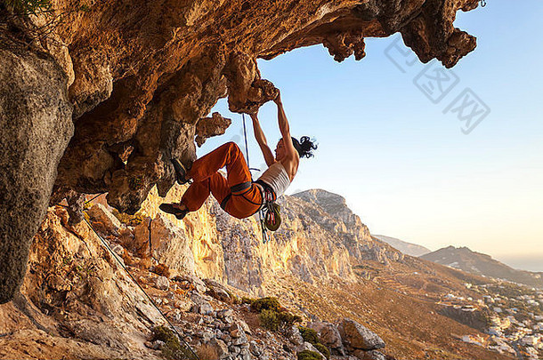 年轻的女岩石登山者悬崖日落