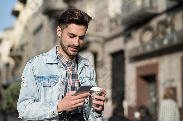 年轻的男人。喝咖啡智能手机城市