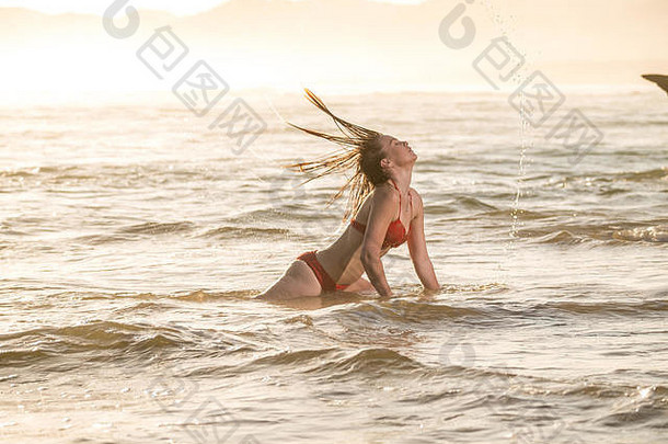 金发女郎女人穿着红色的比基尼有趣的嬉戏海洋