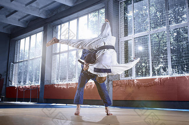 两名柔道选手在搏击俱乐部练习武术时展示了技巧。这两个穿着制服的健康男子。格斗、空手道、训练、艺术、运动员、竞赛理念