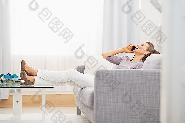 坐在沙发上讲手机的快乐年轻女子