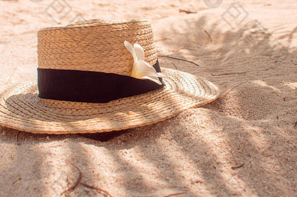 沙上草帽，防晒理念。戴着帽子和棕榈叶的静物画，岛上的海滩度假。