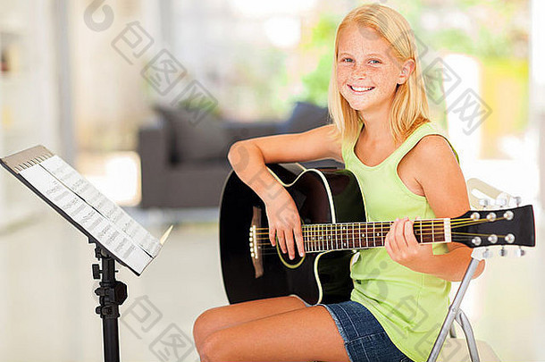 快乐的13岁以下的女孩练习吉他首页