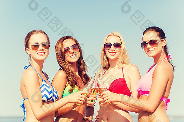 一群微笑的年轻女子在海滩上喝酒
