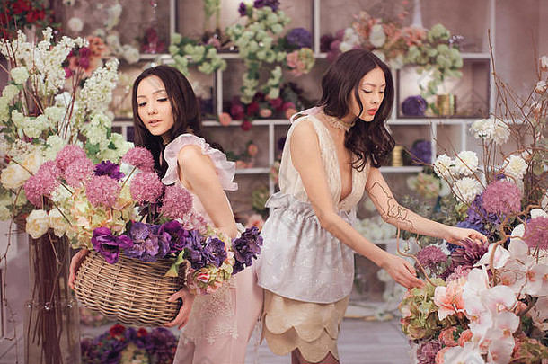 美丽的亚洲女花匠们在花店里愉快地工作着，那里有很多春天的鲜花