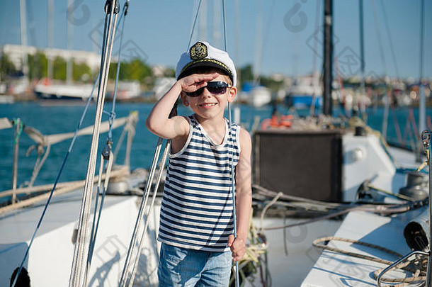 夏日海港游艇板上戴着船长帽的可爱快乐的孩子