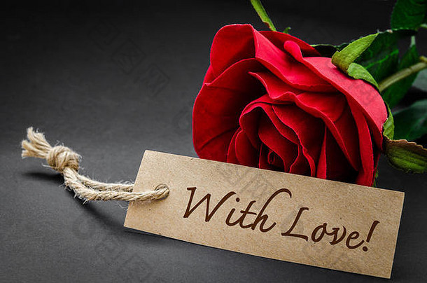 在回收的棕色纸上写着爱的字眼，在黑色纸上写着红玫瑰。